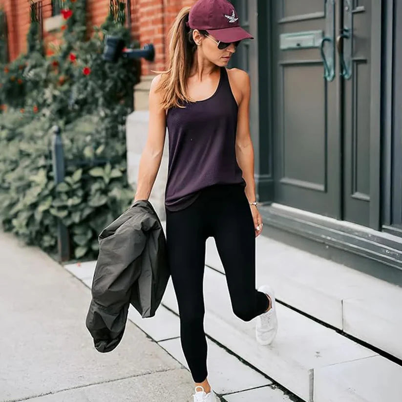Woman in black leggings and purple tank top walking down steps with a jacket in hand.